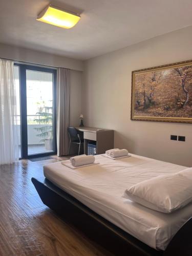 a bedroom with a large bed with a desk and a window at The Touch of the Sea in Durrës