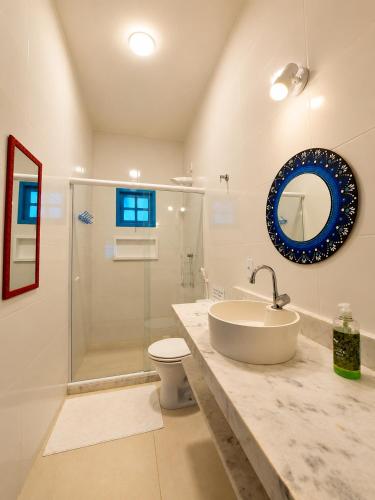 a bathroom with a sink and a toilet and a mirror at Piratas Guest Rooms II in Búzios