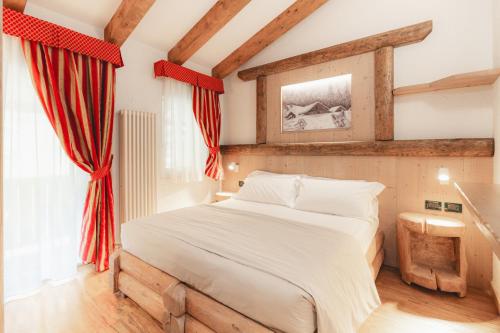 a bedroom with a large bed with red curtains at Hotel Selva in Folgarida