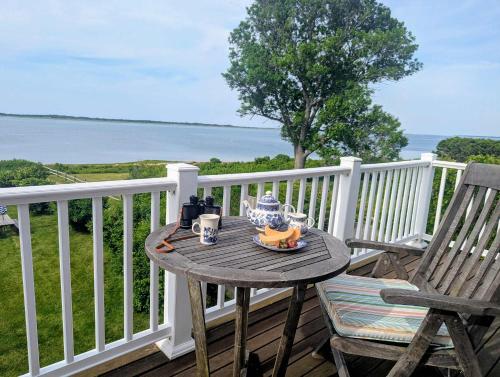 a table on a deck with a view of the water at Barnstable Harbor Home in Barnstable