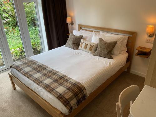 a bedroom with a bed with white sheets and pillows at Gara-Ni Bed & Breakfast in Fort William