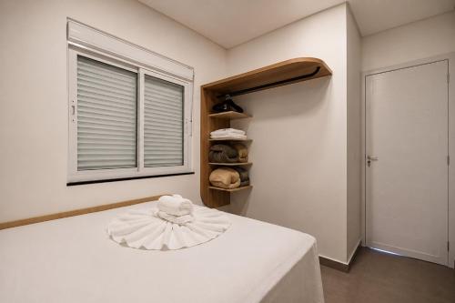 a bedroom with a white bed and a window at Yolanda Flats in Foz do Iguaçu