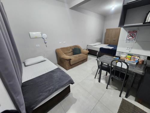 a room with a bed and a chair and a table at Yama Hospedagem e Moradia in Paranavaí