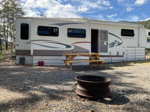 an rv with a wooden table and a picnic table at Doug's Emporium and Riverside Cabins in Hedley