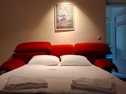 a bed with a red headboard and white pillows at Plomari Rum Evi in Plomari