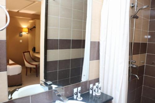 a bathroom with a tub and a sink with a mirror at Clarion Hotel Nairobi in Nairobi