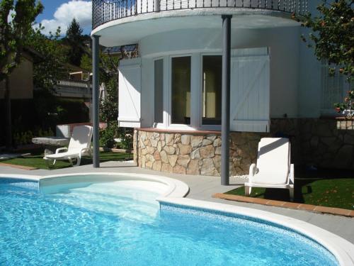 a swimming pool with two chairs and a house at CasasMontseny in Arbúcies