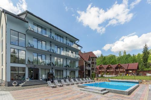 a hotel with a swimming pool in front of a building at Хатинка у Румуна in Tatariv