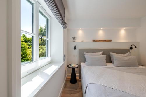 a white bedroom with a bed and a window at Meersalz in Tinnum