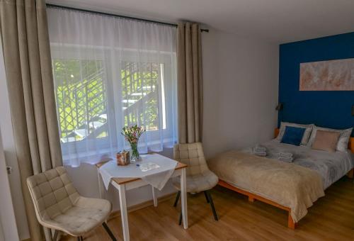 a bedroom with a bed and a table and chairs at Apartamenty Nad Rzeką in Polanica-Zdrój