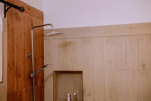a shower in a bathroom with a wooden wall at Avana Home in Arusha