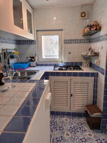a kitchen with blue and white tiles and a sink at Vic e Vicariell in Gaeta