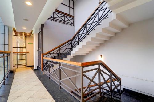 a staircase in a building with wood and metal railing at Hotel O by OYO REFRESH INN & SUITES in Kozhikode