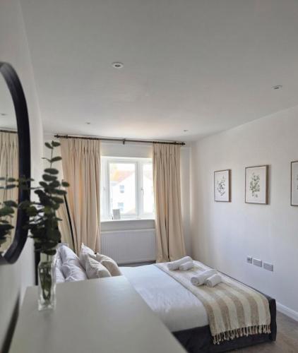 a white bedroom with a bed and a window at River Breeze BALCONY 2 in Littlehampton