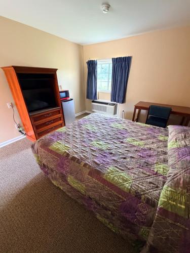 a bedroom with a bed and a dresser and a television at Ranch House Motel in Marksville