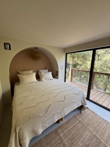 a bedroom with a large bed and a large window at Domaine d'Olga - Lodges & SPA in Aniane
