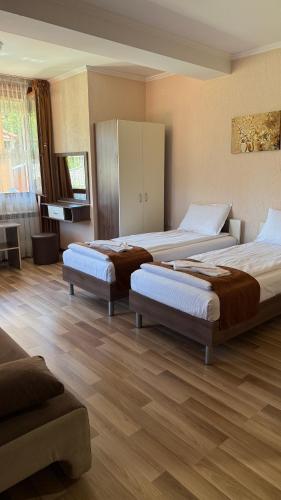 two beds in a room with wooden floors at Къща за гости Гаджакови in Devin