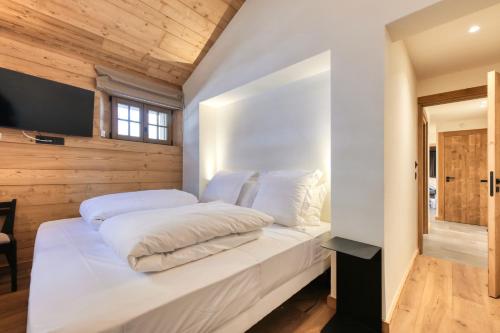 a white bed in a room with wooden walls at Le Chalet Remy in Saint-Gervais-les-Bains