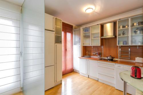 cocina con armarios blancos y suelo de madera en Sancho IV, en Zamora