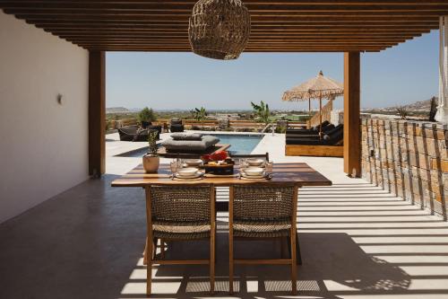 a wooden table and chairs on a patio with a pool at Stone Waves Αpartments & Villas in Agios Arsenios