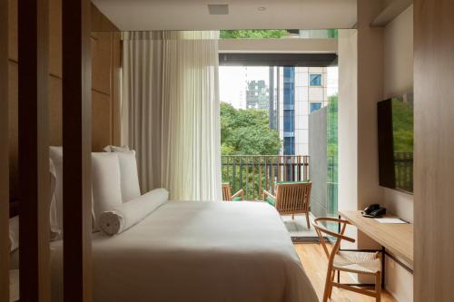 a bedroom with a bed and a balcony with a window at v3rso Jardins in São Paulo