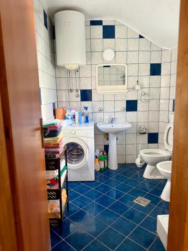 a blue tiled bathroom with a sink and a washing machine at Milovan in Cetinje
