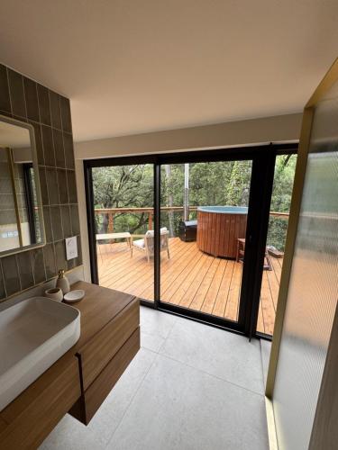 a bathroom with a large sliding glass door to a deck at Domaine d'Olga - Lodges & SPA in Aniane