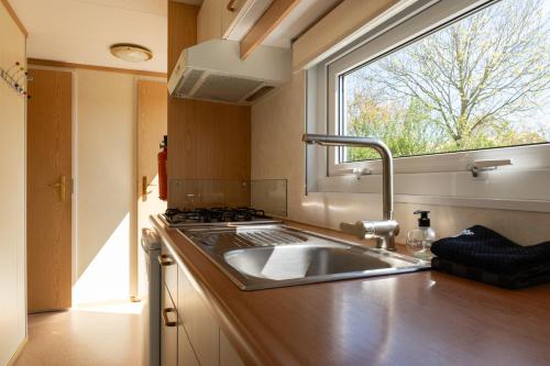 a kitchen with a sink and a window at chalet de kievit in Serooskerke