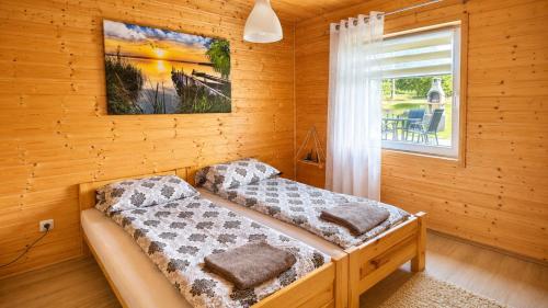 two beds in a wooden room with a window at Domki nad Soliną 665-189-444 OGRZEWANE in Solina