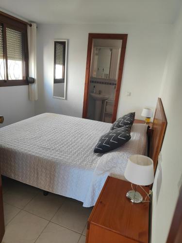 a bedroom with a bed and a table with a lamp at La Perla in Almuñécar