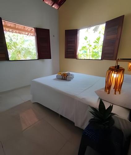 a bedroom with a white bed with two windows at Villa of the Palm Trees in Icaraí