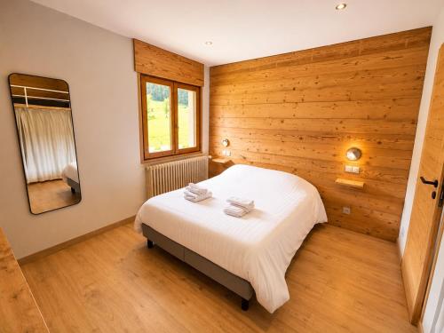 a bedroom with a white bed in a wooden wall at *** Le Refuge *** Logement standing Megève in Demi-Quartier