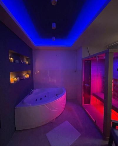 a white tub in a room with purple lights at Apartman Spa Bačka in Bačka Palanka