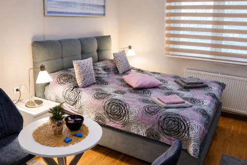 a bedroom with a large bed with pink pillows and a table at Apartman Spa Bačka in Bačka Palanka