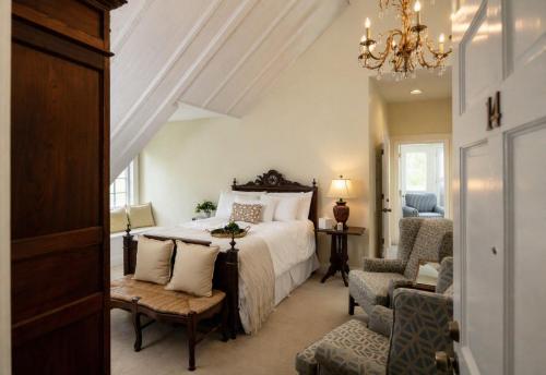 a bedroom with a bed and a chair and a chandelier at The Edenton Collection – Granville Queen Inn in Edenton