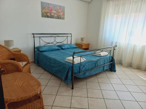 a bedroom with a bed with blue sheets and a chair at IL MELOGRANO Rooms in Vignacastrisi