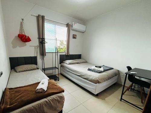 a bedroom with two beds and a desk and a window at Apto c TV Streaming Ar Wifi e Piscina in Ananindeua