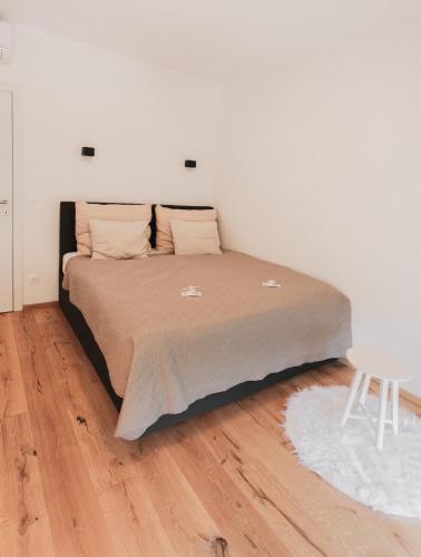 Una cama en un dormitorio con suelo de madera. en Genuss Apartment Basic, en Purbach am Neusiedlersee