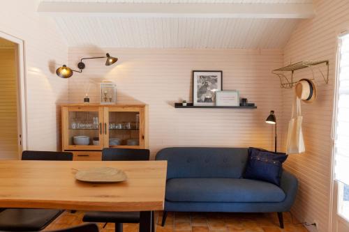 a living room with a blue couch and a table at Domaine de Guillaume Chalet 4 Pers in Auquainville