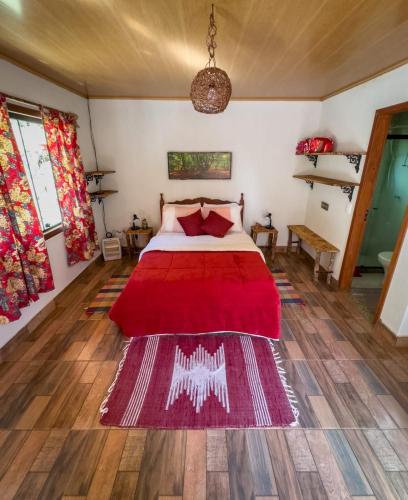 a bedroom with a bed with a red blanket at POUSADA CHALÉS DA GROTA de SÃO PEDRO DA SERRA- NOVA FRIBURGO in Nova Friburgo