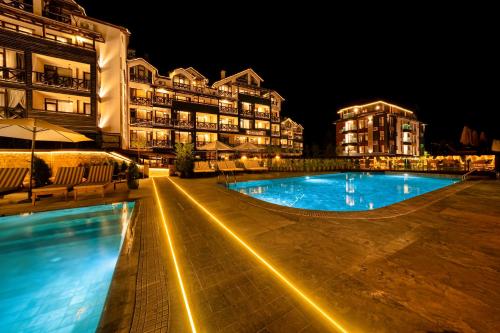 a swimming pool in front of some buildings at night at Premier Luxury Mountain Resort in Bansko