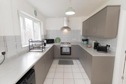 a kitchen with white cabinets and a counter top at Blackthorne House in Walsall