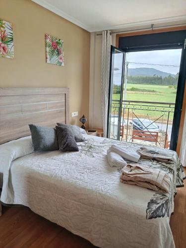 a bedroom with a large bed and a large window at Playa Reinante SPA in Barreiros