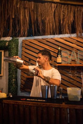 a man is standing at a bar smoking a pipe at Piano Piano hostel in Pipa