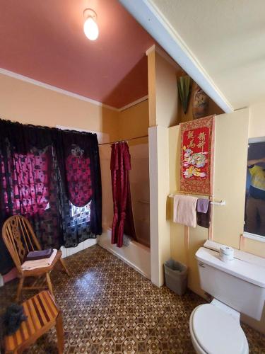 a bathroom with a toilet and curtains and a chair at The Inn at Castle Rock in Bisbee