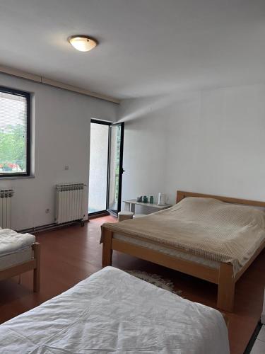 a bedroom with two beds and a large window at Nedzarici sobe in Sarajevo