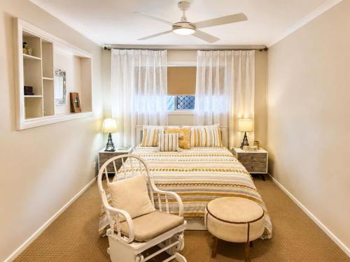 a bedroom with a bed and a chair and a window at William's on William - Stylish 2 Bedroom Haven in Ormiston