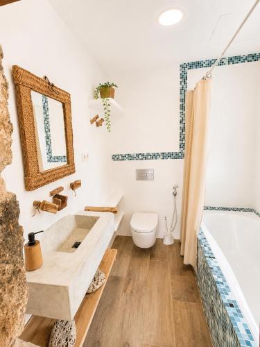 a bathroom with a sink and a tub and a toilet at Latidos del mar in Denia