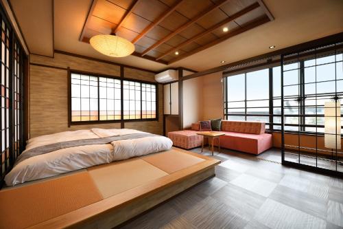 ein Schlafzimmer mit Bett, Sofa und Fenstern in der Unterkunft Hanano Koyado Jyu-bei in Toba