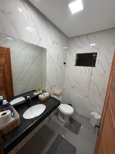a bathroom with a sink and a toilet and a mirror at Casa Pé no Sal in Salinópolis